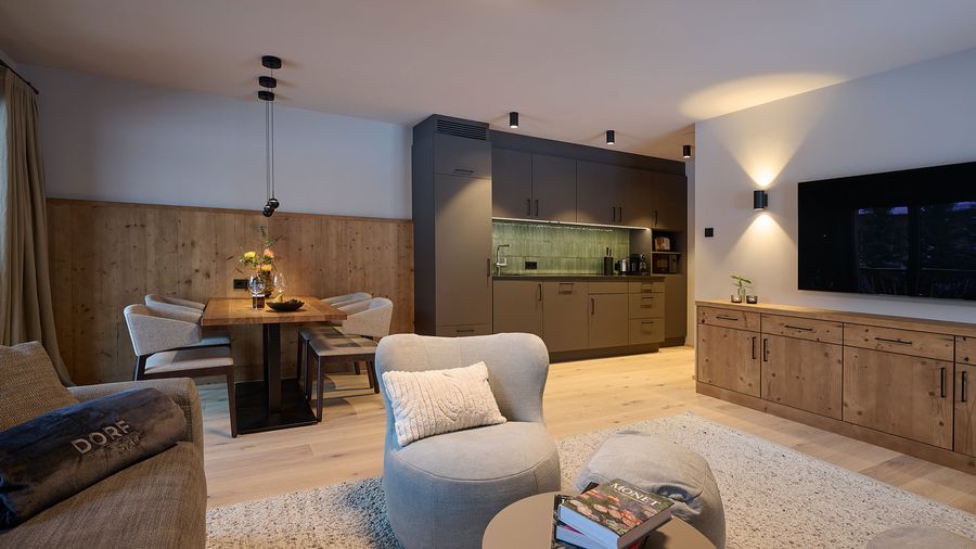 Wohnbereich DORF 570 Offener Wohn- und Essbereich mit moderner Küche, Holzdetails, TV und gemütlichen Sitzmöbeln