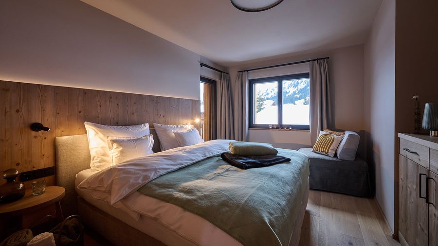 Schlafzimmer DORF 570 Schlafzimmer mit Holzdetails, großem Bett und Bergblick aus dem Fenster